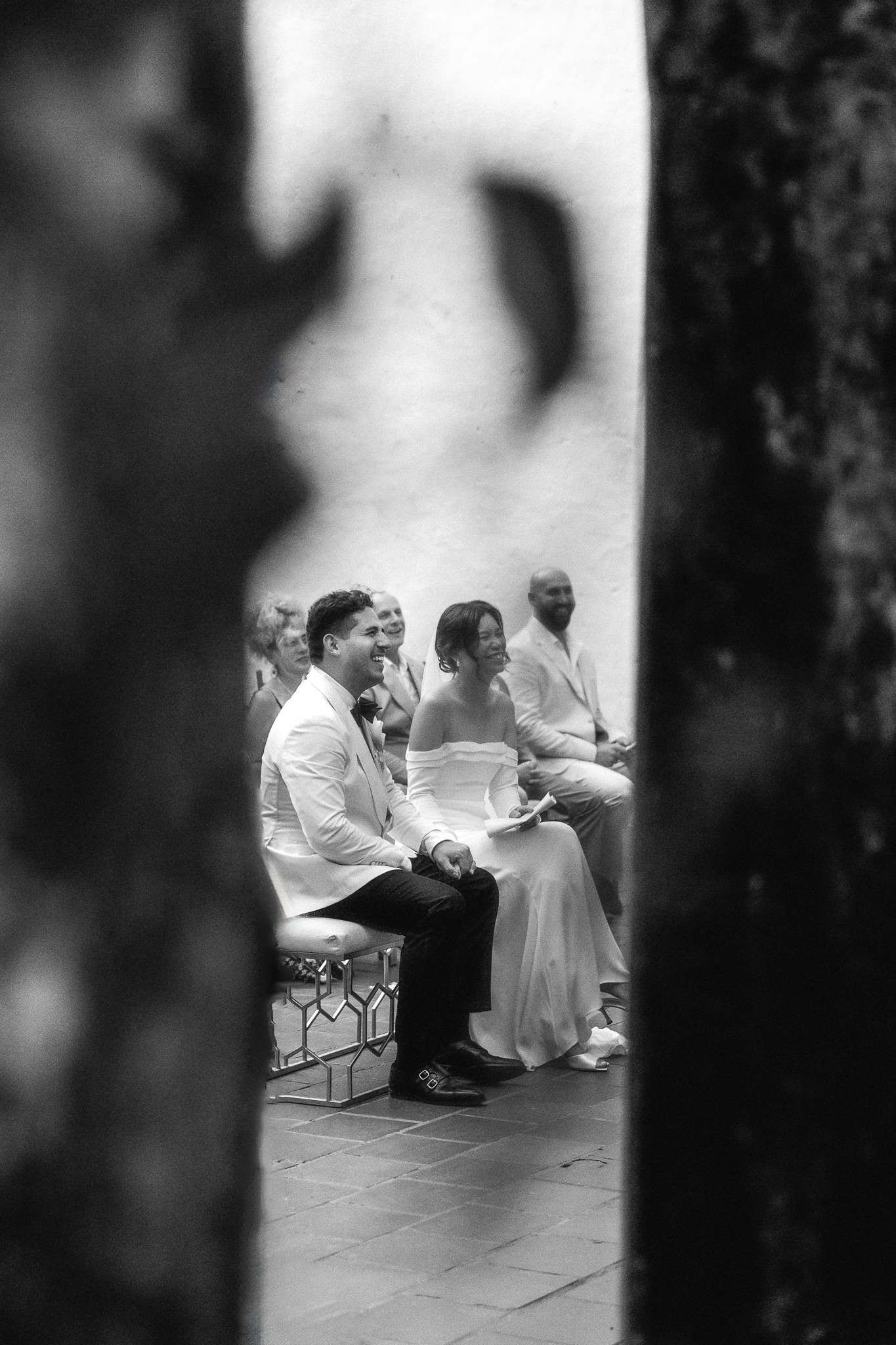 wedding ceremony being framed by two palm trees and showing the couple laughing during the ceremony