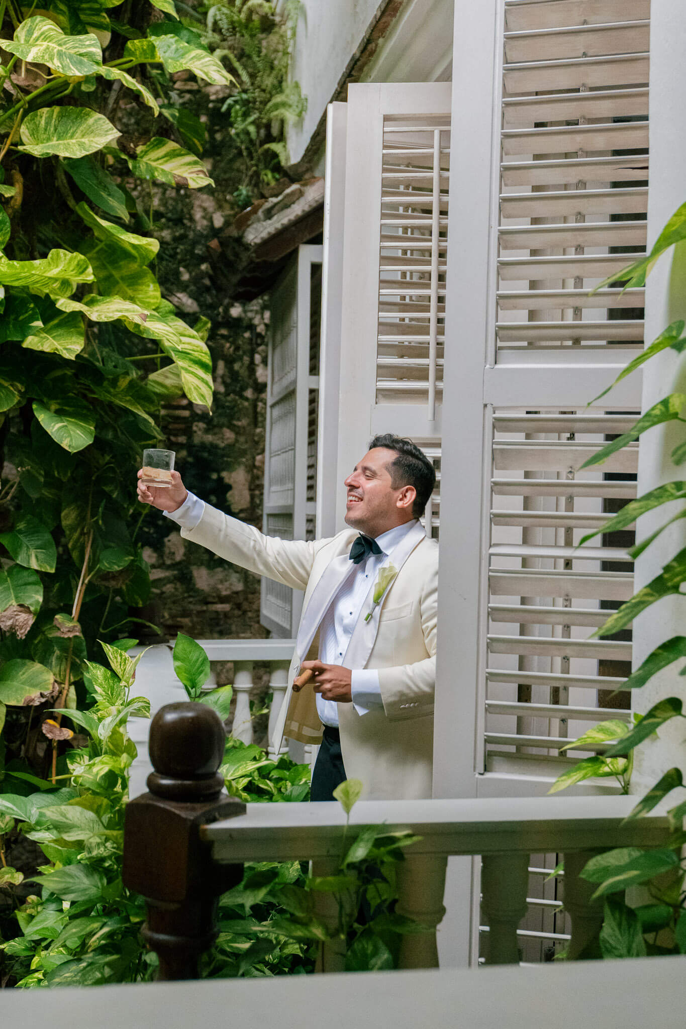 cartagena wedding groom balcony photo cheers to his guest with a vine growing background