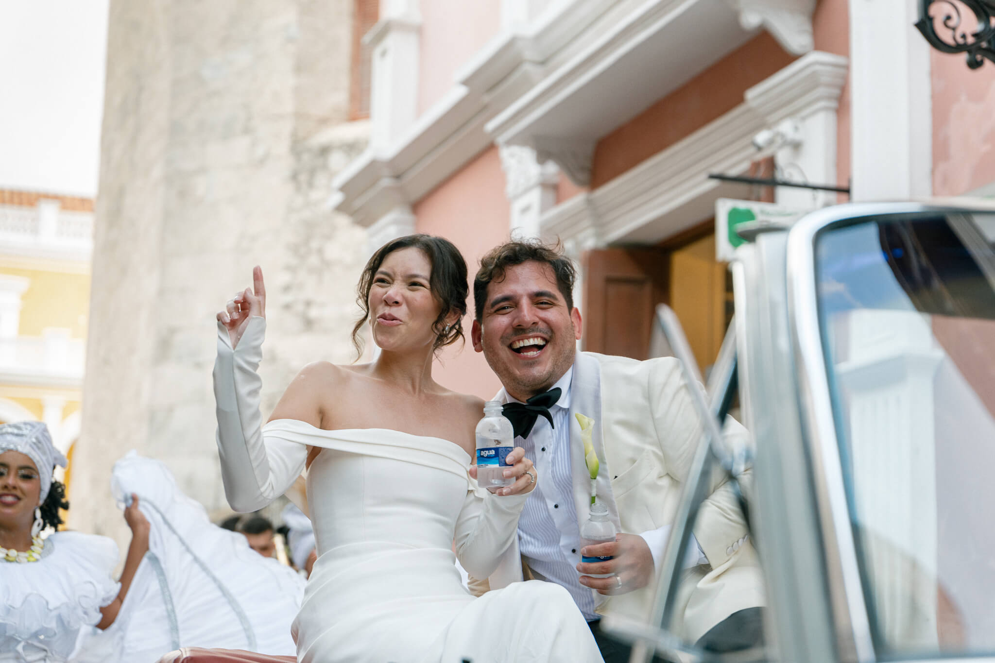 happy wedding couple cheering and having a great time seeing their quests in cartagena colombia streets
