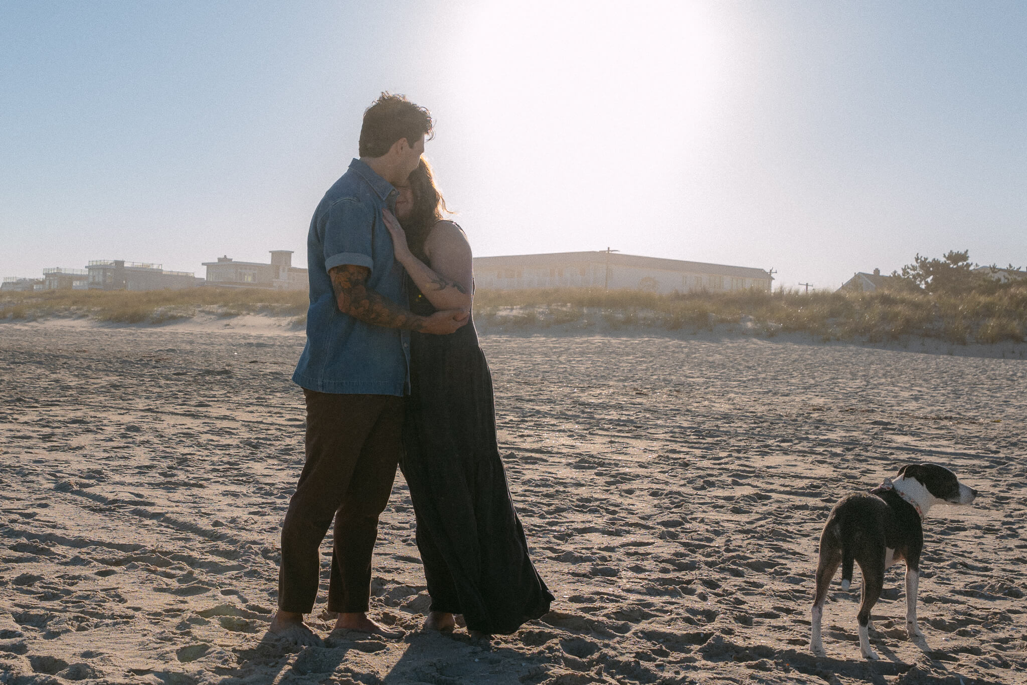 long beach island proposal with couple by the beach with thier dog celebrating and embracing with an intimate hug